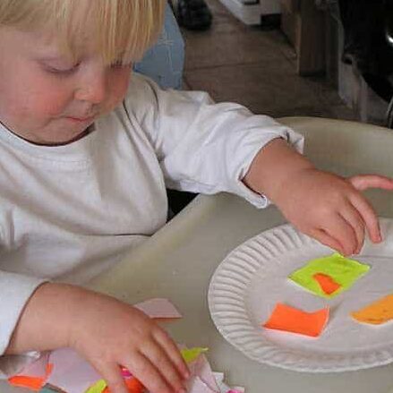 toddler sticking paper on a paper plate