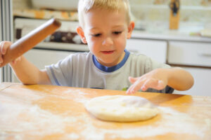 toddler rolling out pizza dough