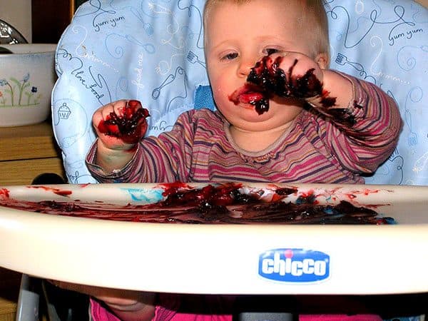 young toddler in a high chair with finger paints