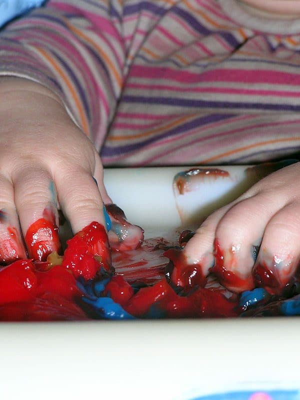 10-month-old baby exploring colour mixing on the high tray using homemade paints