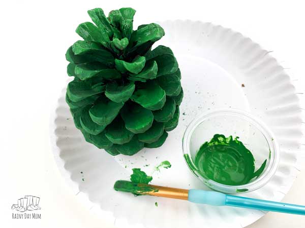 painted green pine cone drying on a paper plate