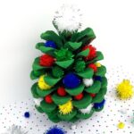 christmas pine cone ornament with pom poms made by a toddler