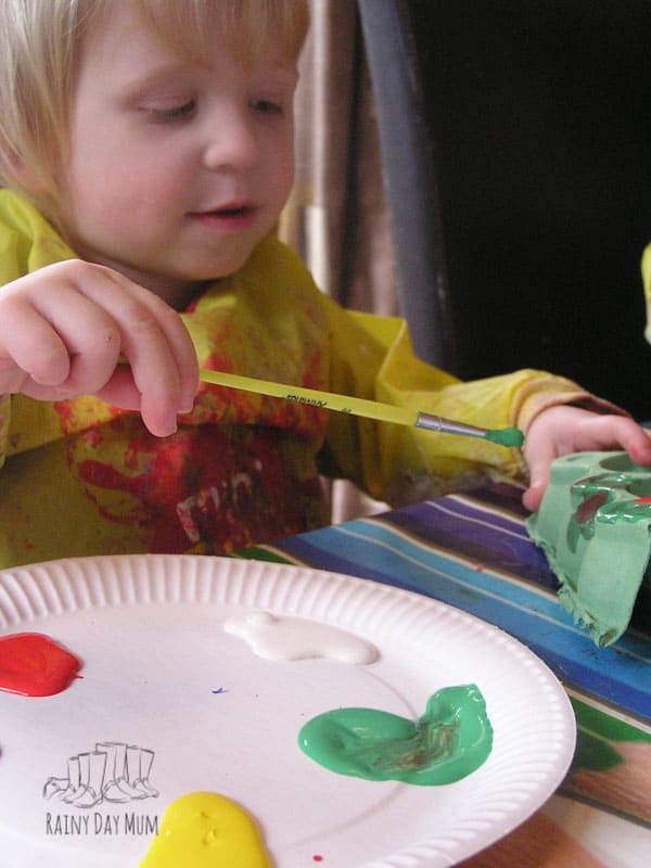 toddler painting egg boxes to create egg box caterpillars that will then grow
