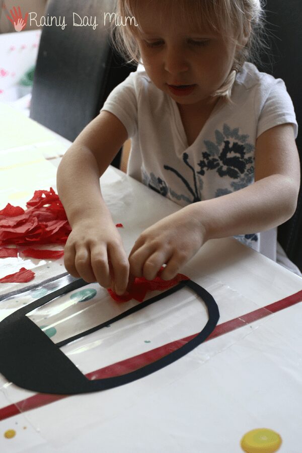 toddler using tissue paper to create a suncatcher
