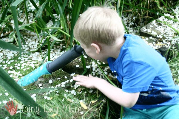 child using the underwater scope from learning resources to see under the water in a pond