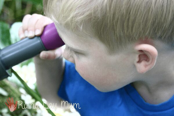 close up of child holding an underwater scope to their eye to view what is happening under the water in the pond.