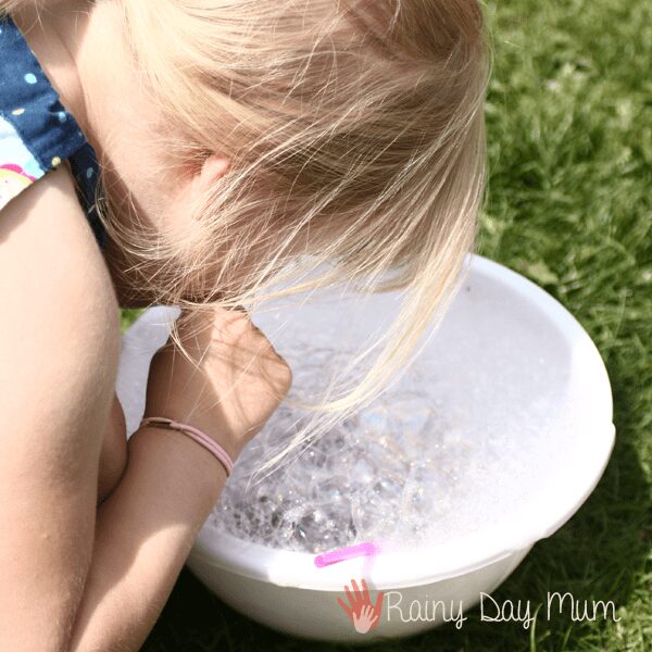 child making bubbles in a bowl with food colouring and water