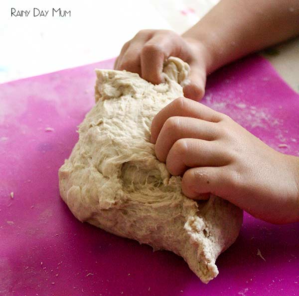 child's hands kneading bread dough on a bright pink mat