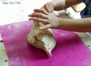 preschooler kneading dough for bread on a pink surface