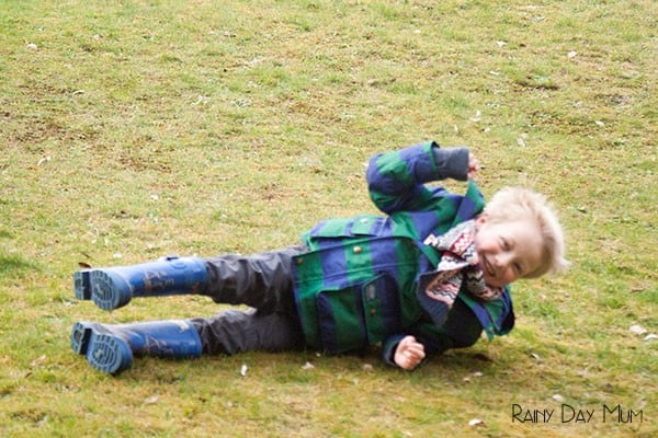 preschooler rolling down a hill in the park