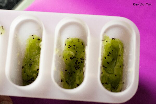 kiwi pulp in a set of ice lolly molds ready to go in the freezer