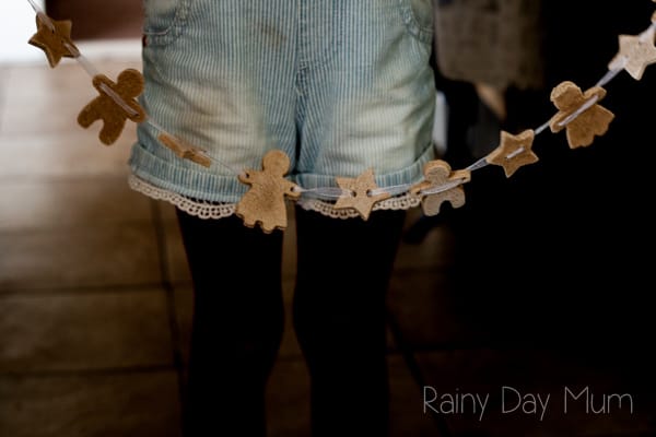 preschooler holding a garland of gingerbread men and women scented salt dough decorations.