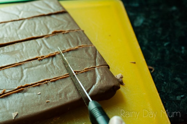 cutting up fudge made in the crockpot with a sharp knife on a yellow chopping board