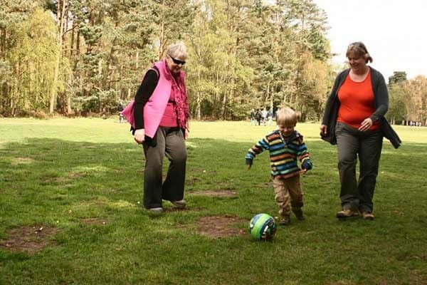 mom, grandma and preschooler playing with a ball in the park