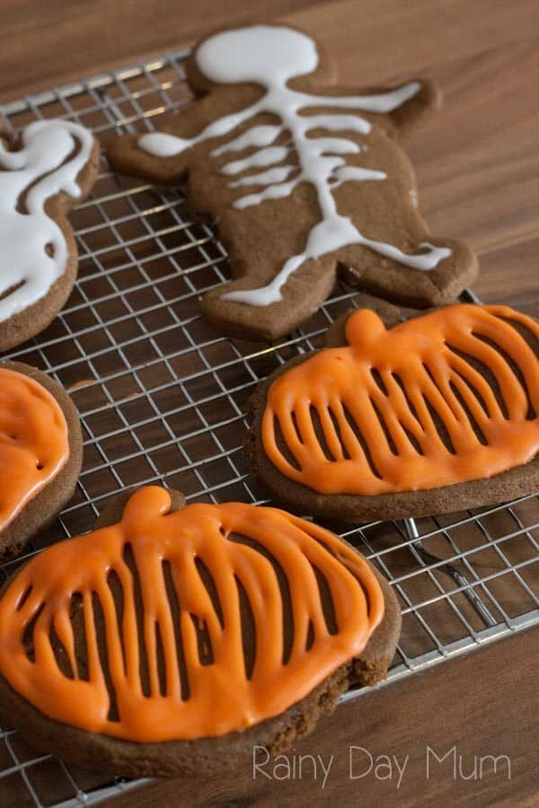 a set of halloween cookies cooling on a cooling wrack in the kitchen that kids have baked and decorated very simply
