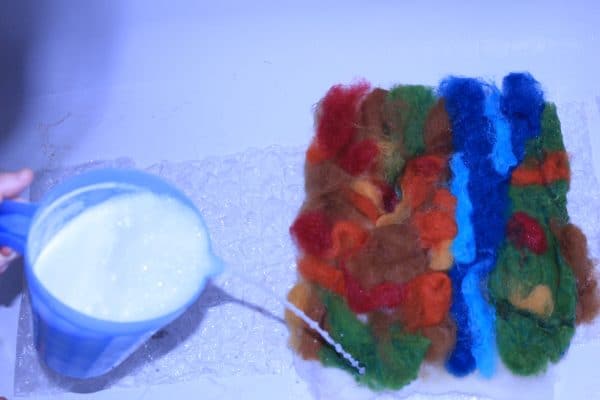 adding soapy water to felt wool roving into an image