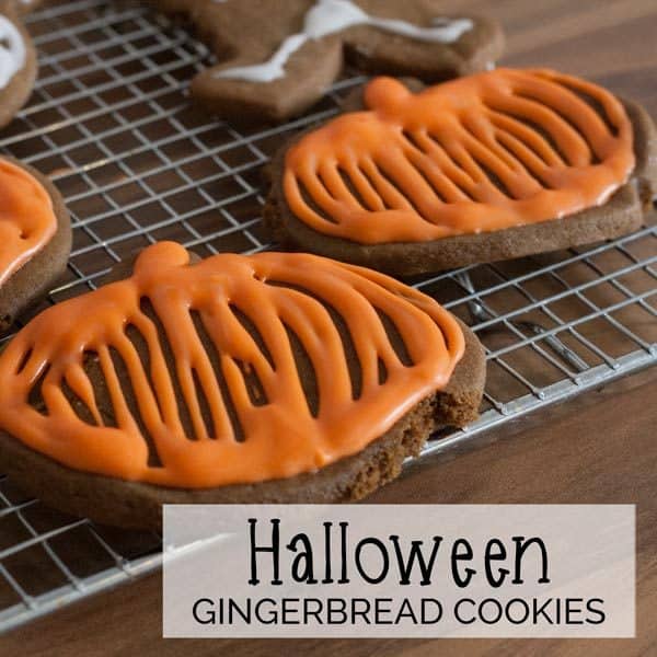 picture of a gingerbread pumpkin cookie with orange royal icing text overlay reads Halloween Gingerbread Cookies