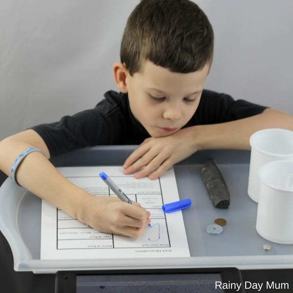 child filling in a rock testing worksheet whilst studying rocks in homeschool
