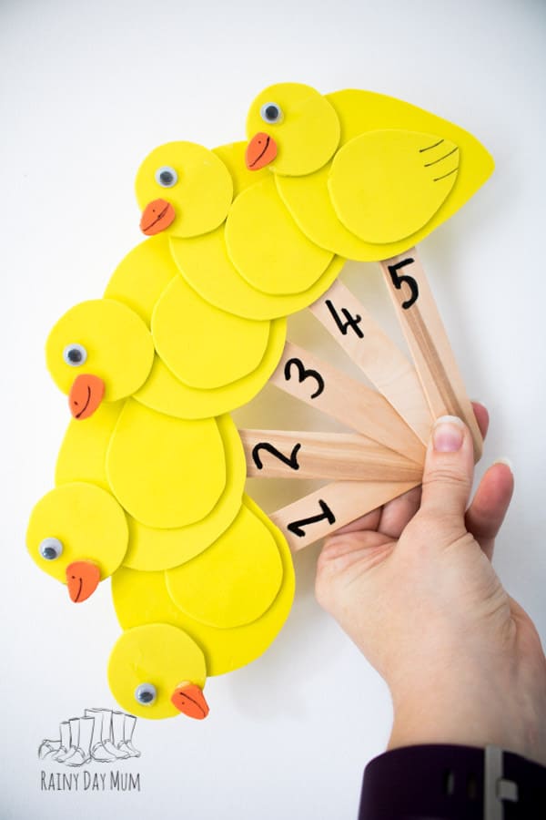 five little swimming ducks on craft sticks with 1 to 5 on the sticks held in a hand for singing the rhyme with kids