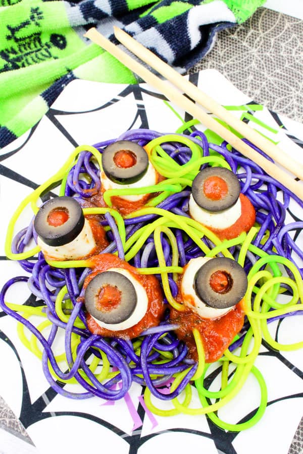 a plate of coloured spaghetti with mozzarella eyeballs for Halloween. Easy recipe that kids can cook themselves