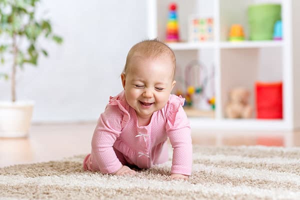 8-month-old baby girl crawling and laughing whilst playing games with her parents
