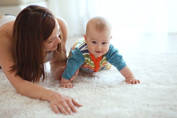 mother and 6 month old baby playing on a textured carpet