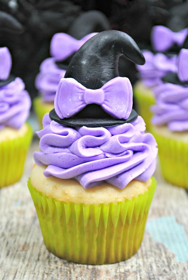 Witches hat cupcake in focus with lilac buttercream frosting