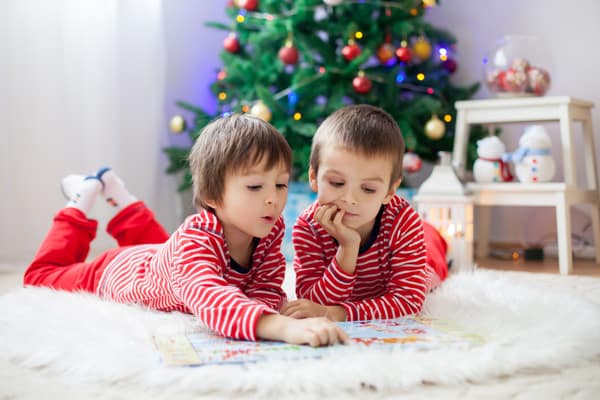 kids reading christmas books infront of the christmas tree