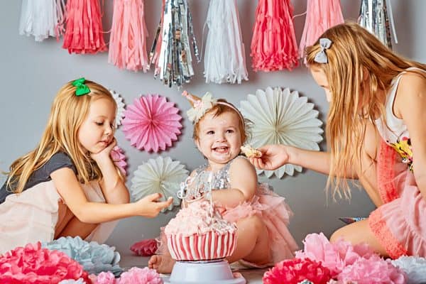 baby girl celebrating first birthday with siblings and mum