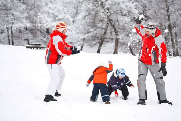 family having fun together in the winter with a simple winter activity snowball fights