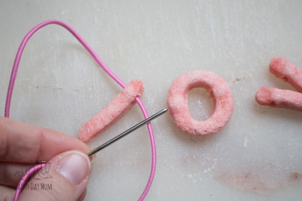 threading letter beads made from salt dough to create a LOVE necklace for Valentines Day