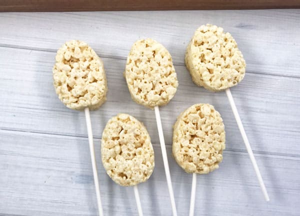 rice krispie treats cut into egg shapes and then added a cake pop stick ready for kids to decorate for simple Easter Party Treats that they will love
