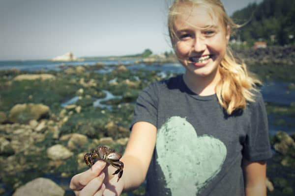 girl holding a crab found in the rock pools on the beach
