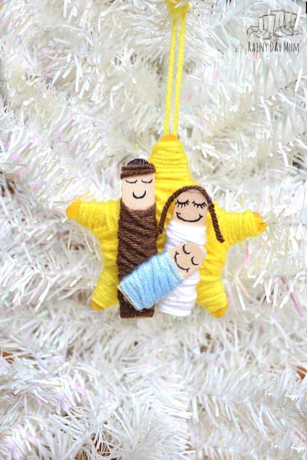 hanging craft stick and yarn nativity ornament on a white christmas tree