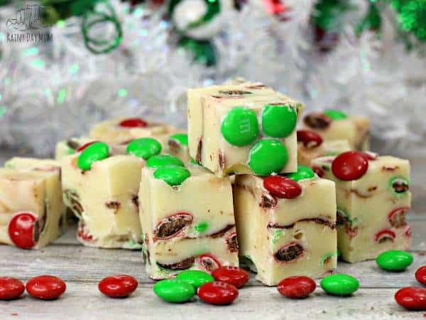delicious white chocolate fudge with green and red m&ms in front of a white Christmas Tree