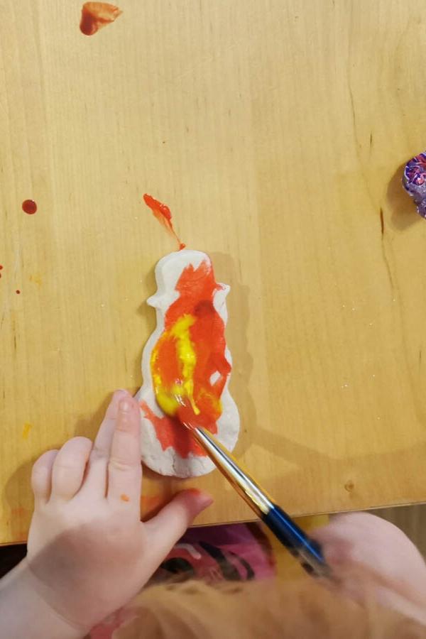 child painting snowmen made with salt dough using ready-mixed kids' paints