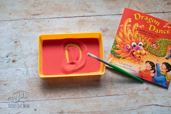 chinese new year writing the letter D from the front cover of Dragon Dance in a sand tray