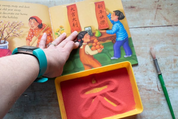 Copying Chinese Symbols from the Dragon Dance Book to write in the sand tray