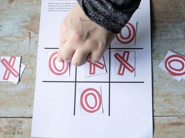 an adult supporting a toddler playing tic tac toe