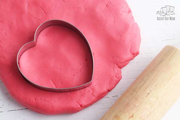 red cherry playdough with a heart cutter and rolling pin ready for play