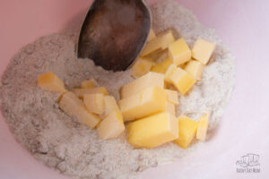 cubed chilled butter ready to make crumble topping in a pink bowl