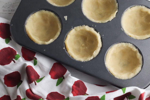 no-roll pastry crust in a muffin tin ready to be filled with apples