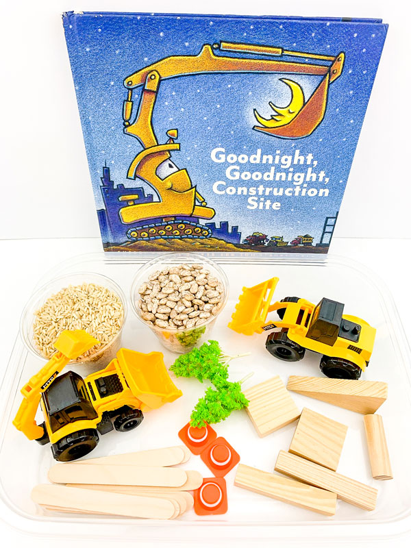 the materials for creating a simple construction sensory tub for kids, trucks, building blocks, trees, brown rice, dried pinto beans and the book Goodnight, Goodnight Construction Site to read alongside the play
