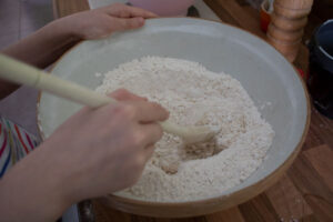 mixing the water into dry ingredients for Viking bread in a bowl with a wooden spoon