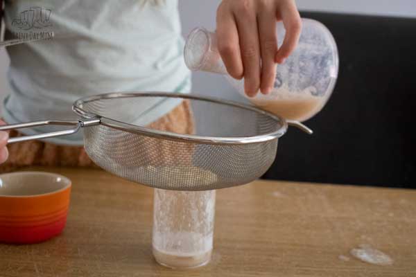 child pouring DNA extraction solution through a sieve