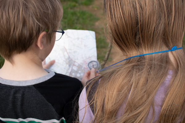 2 kids looking at an OS map and compass on a family orienteering adventure