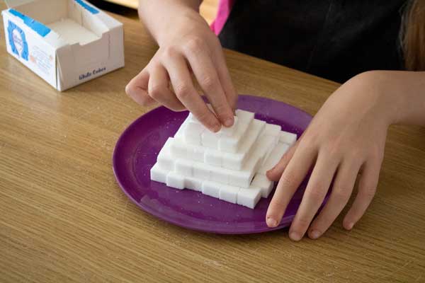child making a sugar cube pyramid on a plate