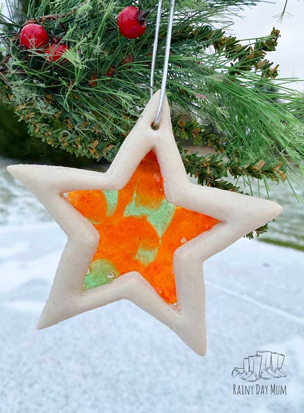 salt dough star with stained glass centre hanging on a christmas tree in the air