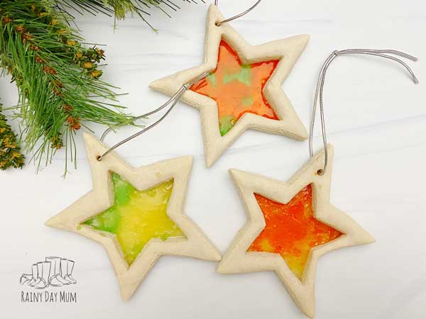 three simple salt dough stars with cut out centres filled with stained glass from hard candy perfect for Christmas ornaments that kids can make