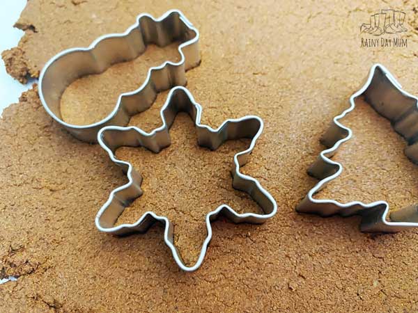 cutting out christmas ornaments from homemade clay using cookie cutters